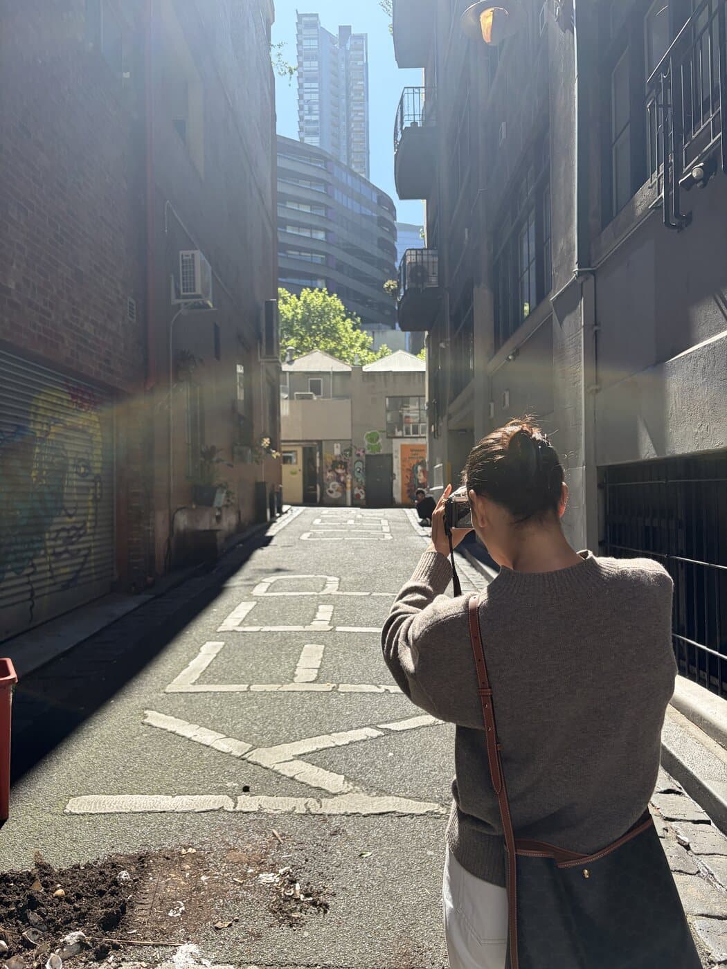 Clara photographing a Melbourne laneway with an OM System OM-3