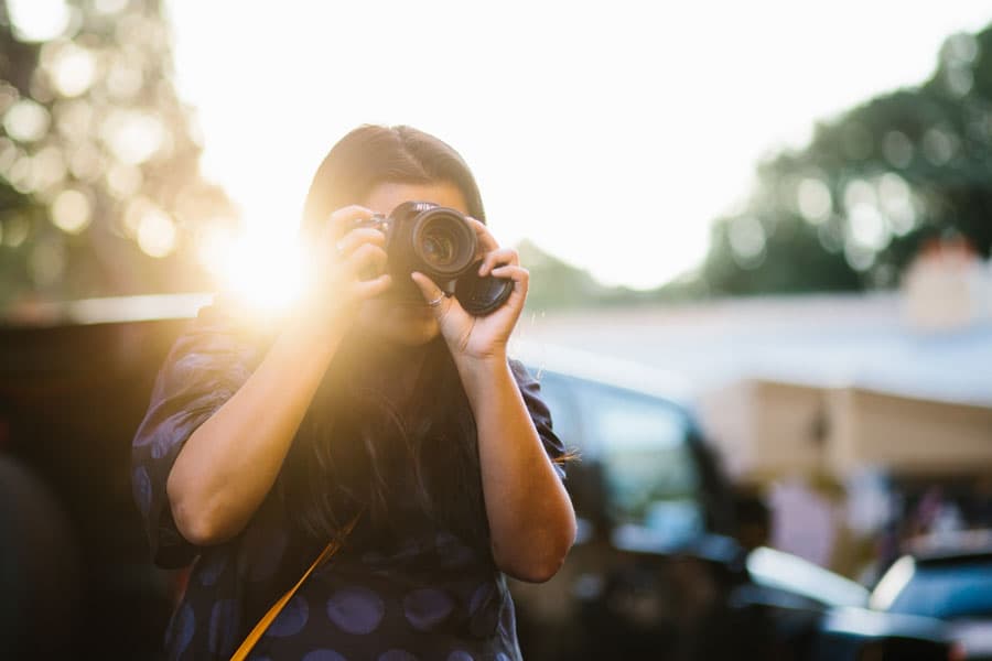 student on a camera course sydney australia. sunset is behind her and she's holding a dslr