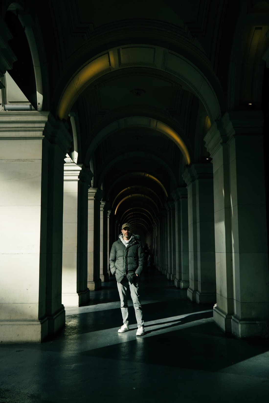 Daniel Bilsborough, founder of DJB Photography School, standing in a beam of light under the arches of a heritage Melbourne CBD colonnade