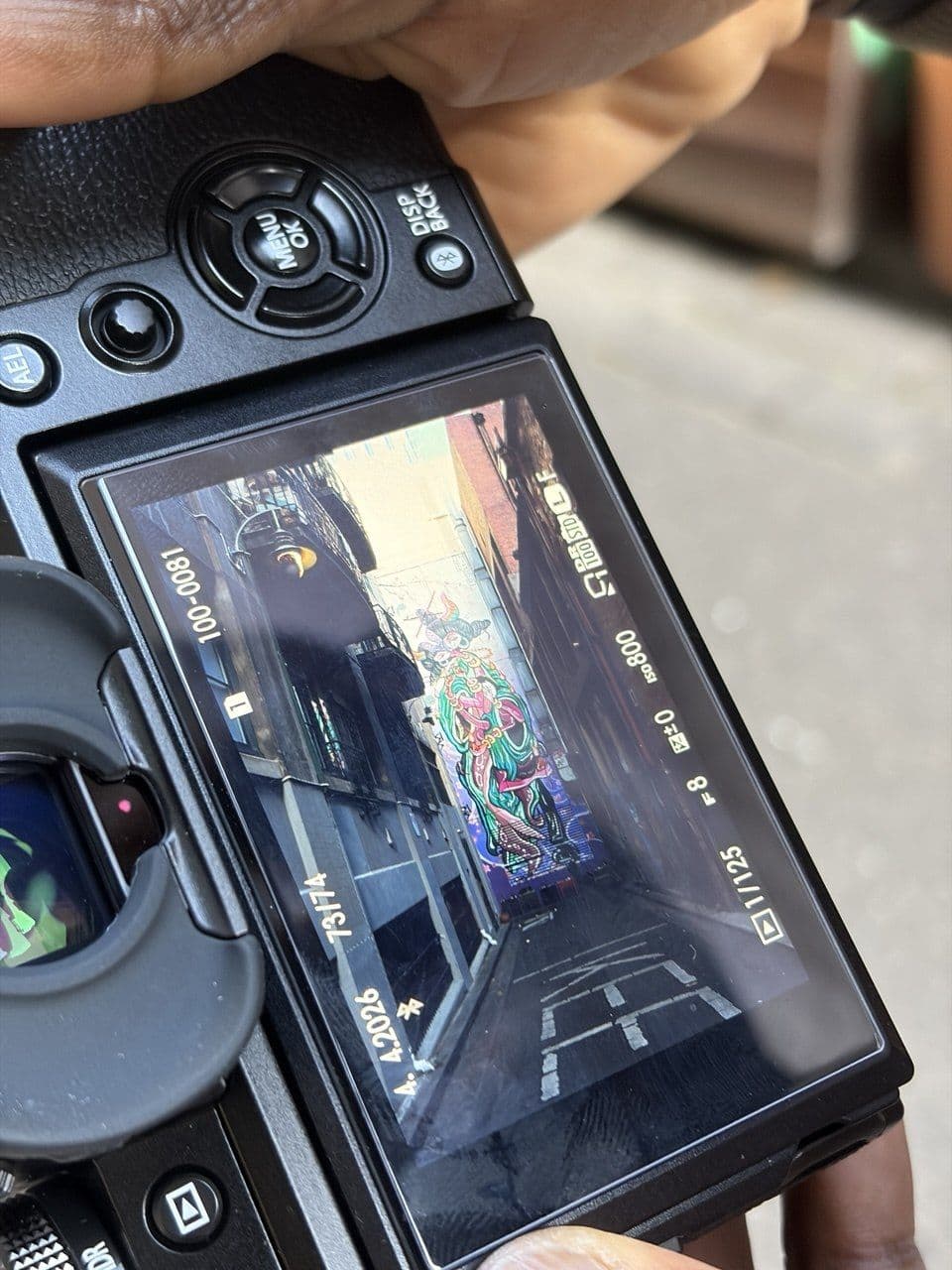 Close-up of Dam's Fujifilm X-T5 rear LCD screen showing a colourful Melbourne laneway composition with graffiti during a photography course