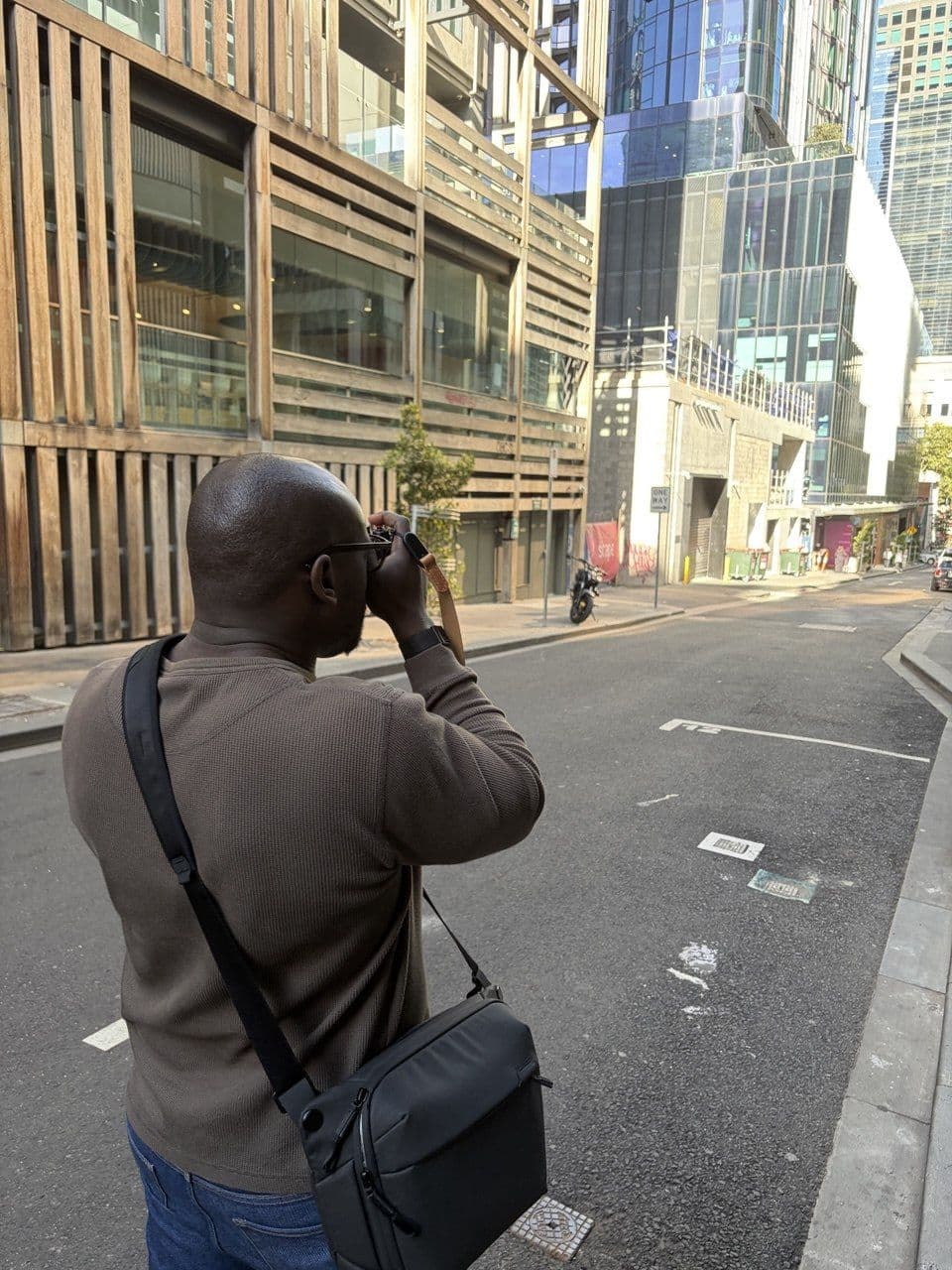 Dam shooting with his Fujifilm X-T5 on a Melbourne city street with modern buildings in the background during a photography course