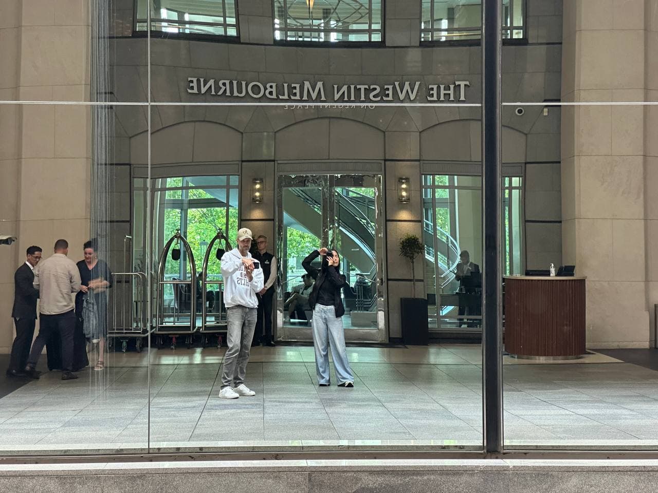 Reflection in The Westin Melbourne glass entrance showing Janet photographing during a Melbourne photography course