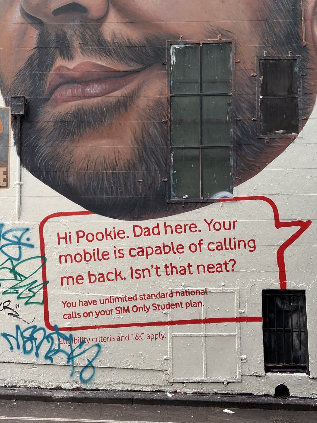 Painted mural of a bearded face with a red speech bubble on a Melbourne wall photographed during a street photography course