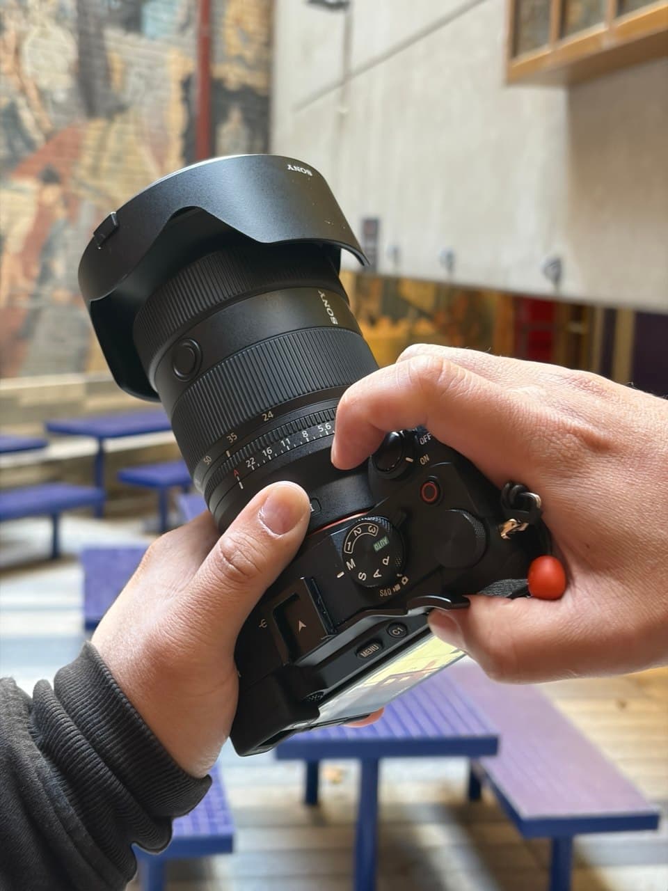 Top-down view of Ron holding a Sony A7CR with the 24-70mm f/2.8 GM II lens mounted, showing the mode dial and control layout