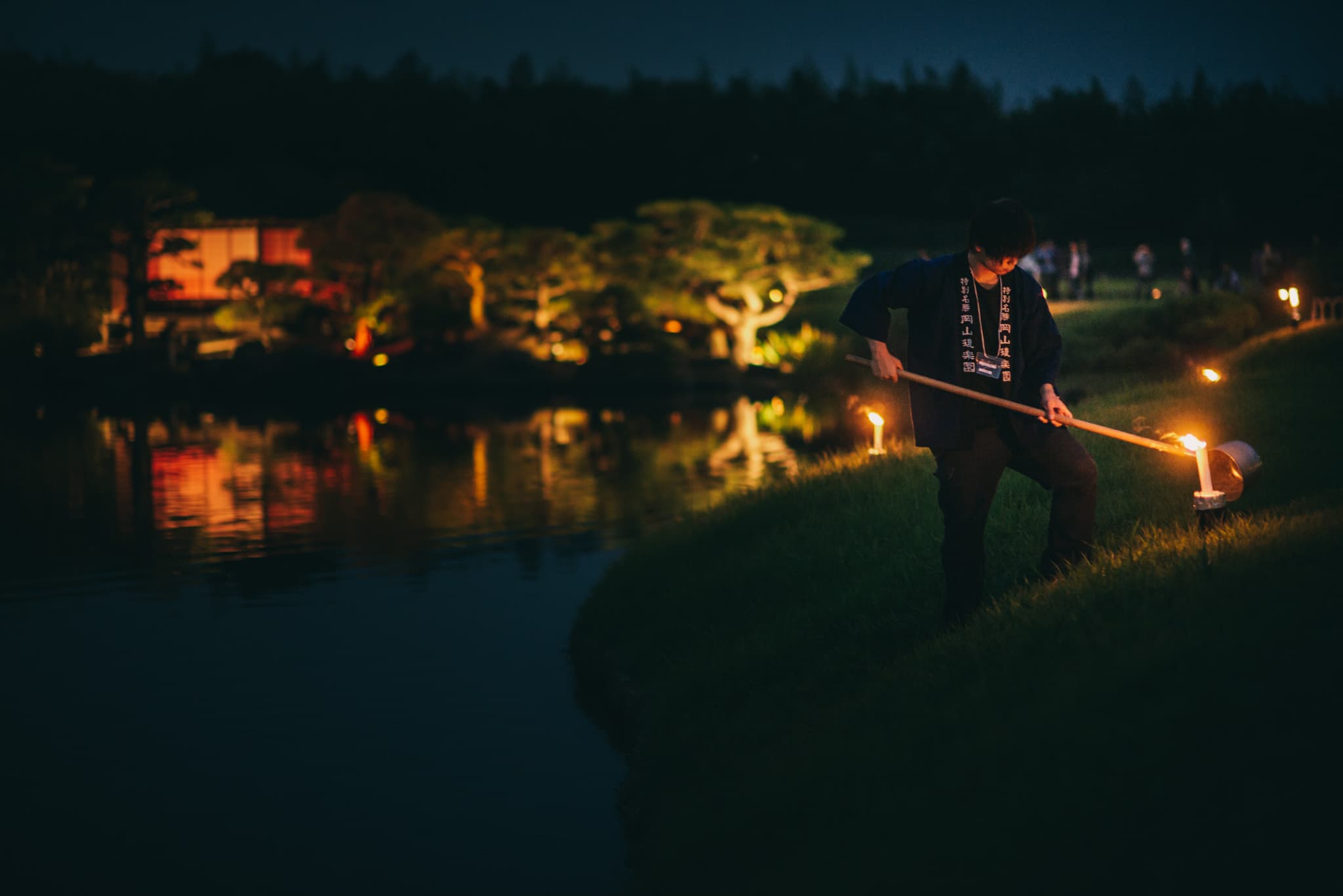 Night photography of a Japanese garden with lantern light reflecting on water
